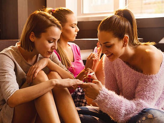 Female friends having a manicure treatment at home and applying nail polish on fingernails.
